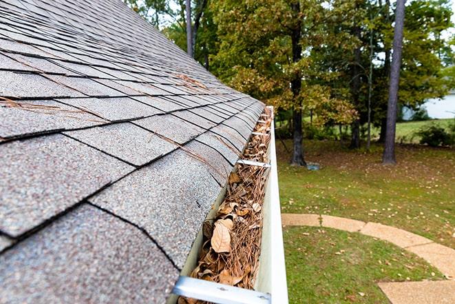 home maintenance worker removing debris from gutters